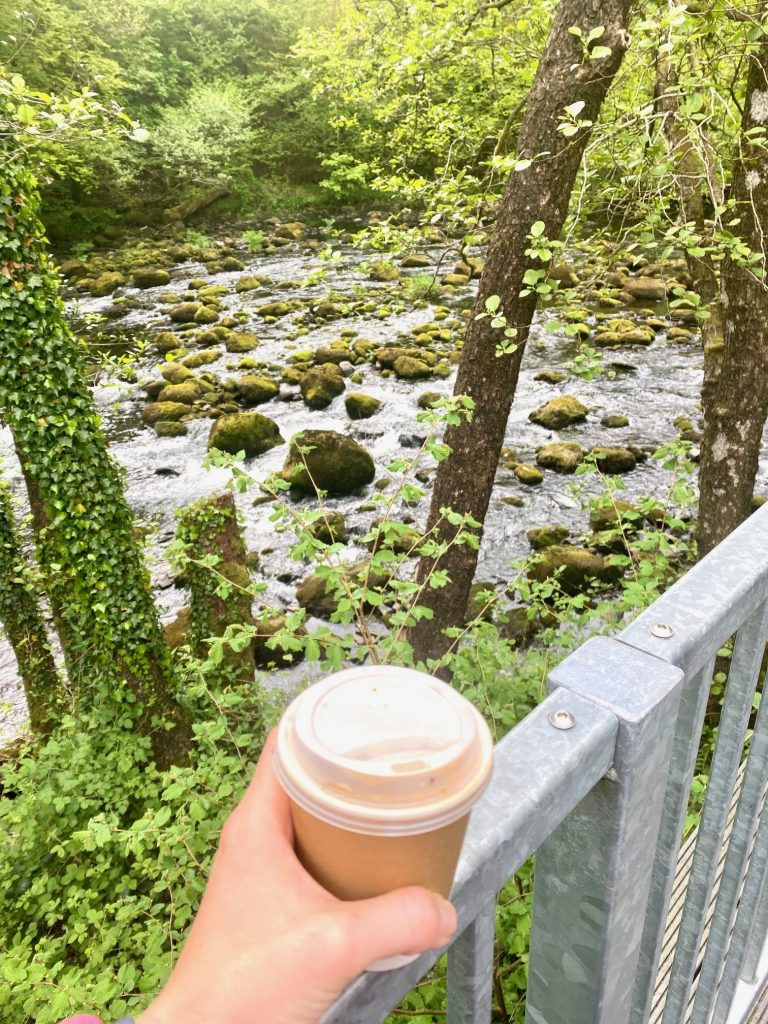 Holding a cup of coffee in front of the River Brathay in Skelwith Bridge