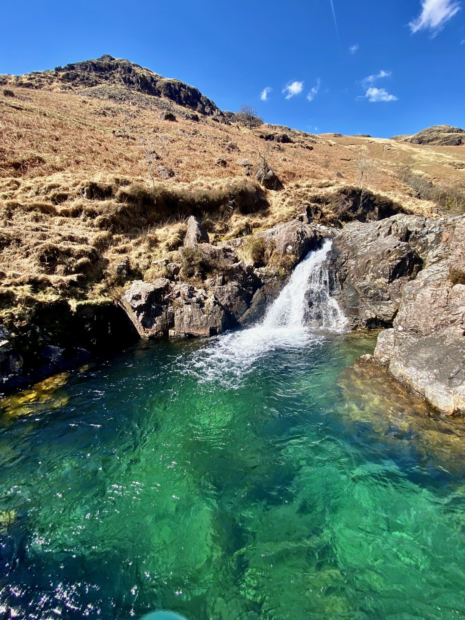 A small waterfall into a pool of turquoise water in The Lake District.