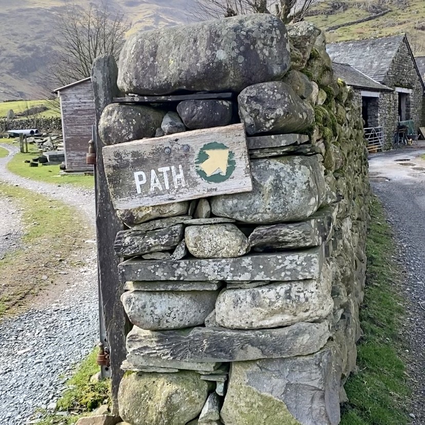 A path on a stone wall pointing to the path on the right.