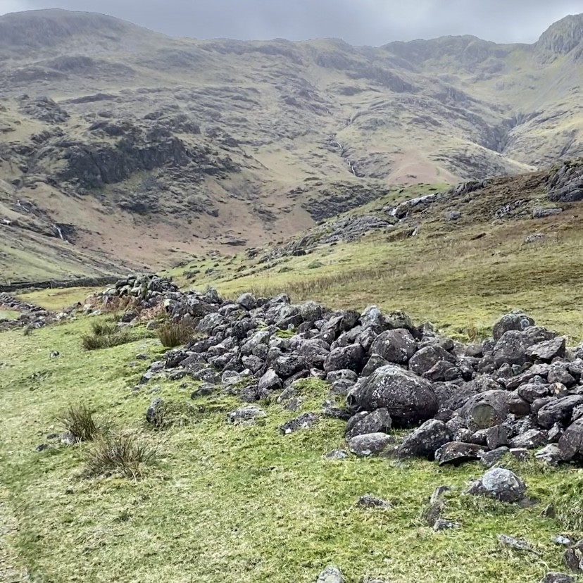A destroyed stone wall with mountains in the distance
