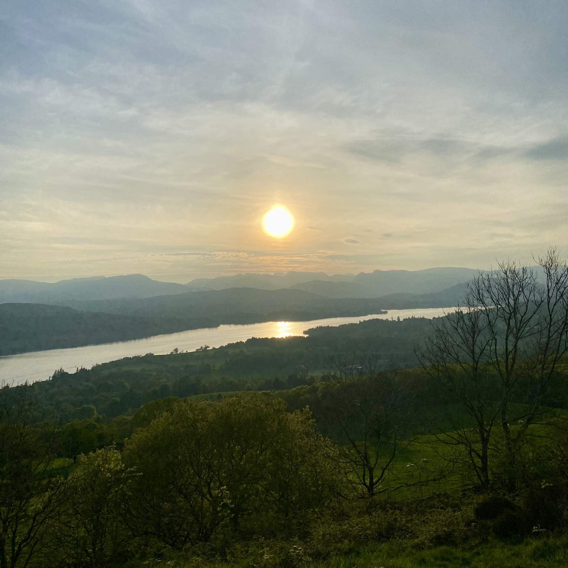 Sunset view from Orrest Head overlooking Lake Windermere and mountains in the distance