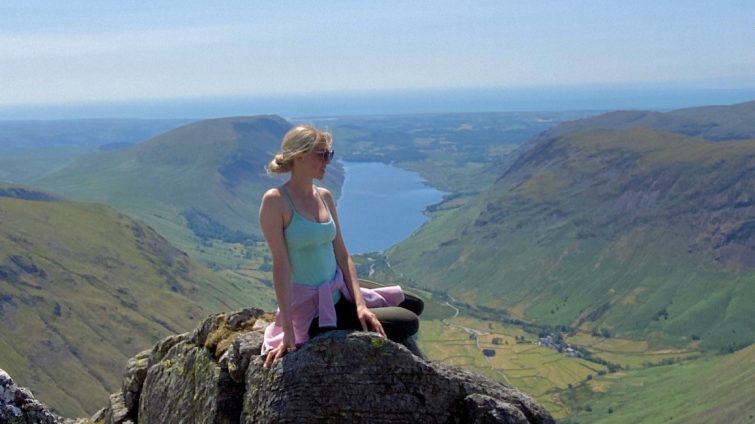 Girl sitting on a rock up a mountain in the Lake District with a lake in the background