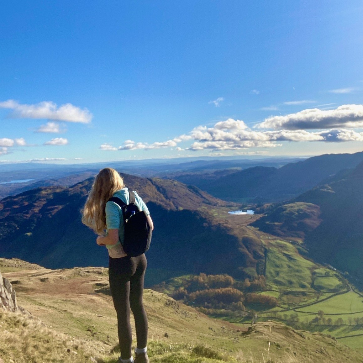 A woman standing on a mountain with mountains in the background.