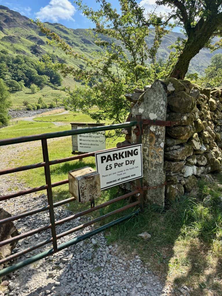 The entrance of Stonethwaite Farm Campsite, with a sign for £5 per day parking and an honesty box